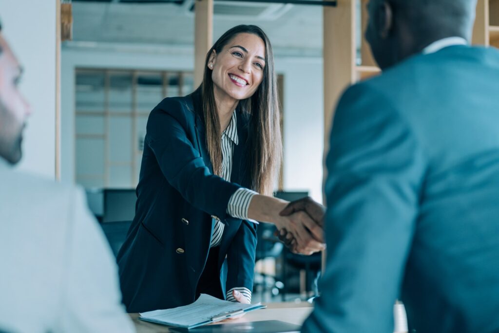 Woman smiling and shaking hands with a man.